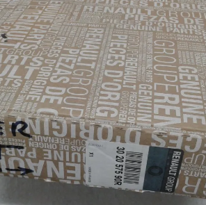 Caja de cartón con el embalaje de piezas originales Renault y una etiqueta de envío en la parte superior.