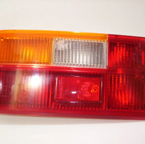 Primer plano de un conjunto de luces traseras de automóvil rojas y ámbar con una sección central transparente.