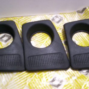 Tres soportes de plástico negro para teléfonos dispuestos sobre una superficie estampada de color amarillo.