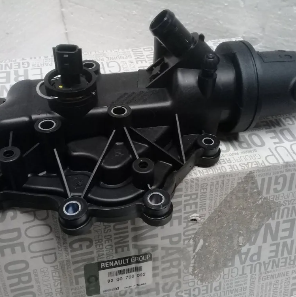 Carcasa de termostato de plástico negro para automóviles con tornillos metálicos sobre fondo de papel impreso.
