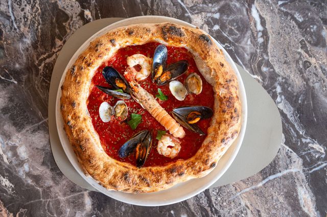 Una pizza con i frutti di mare è su un piatto su un tavolo.
