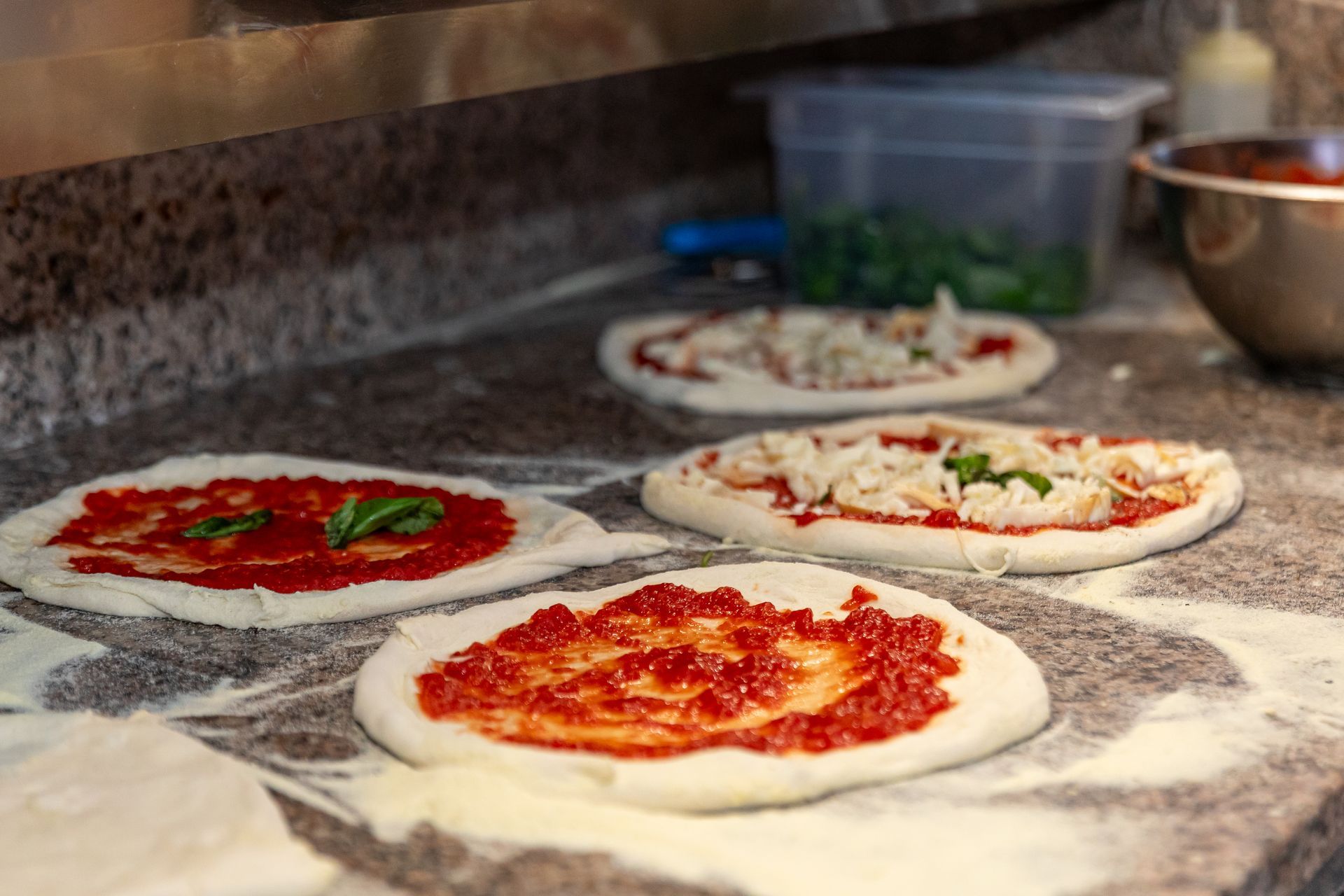 Una persona sta preparando una pizza con salsa di pomodoro e formaggio.