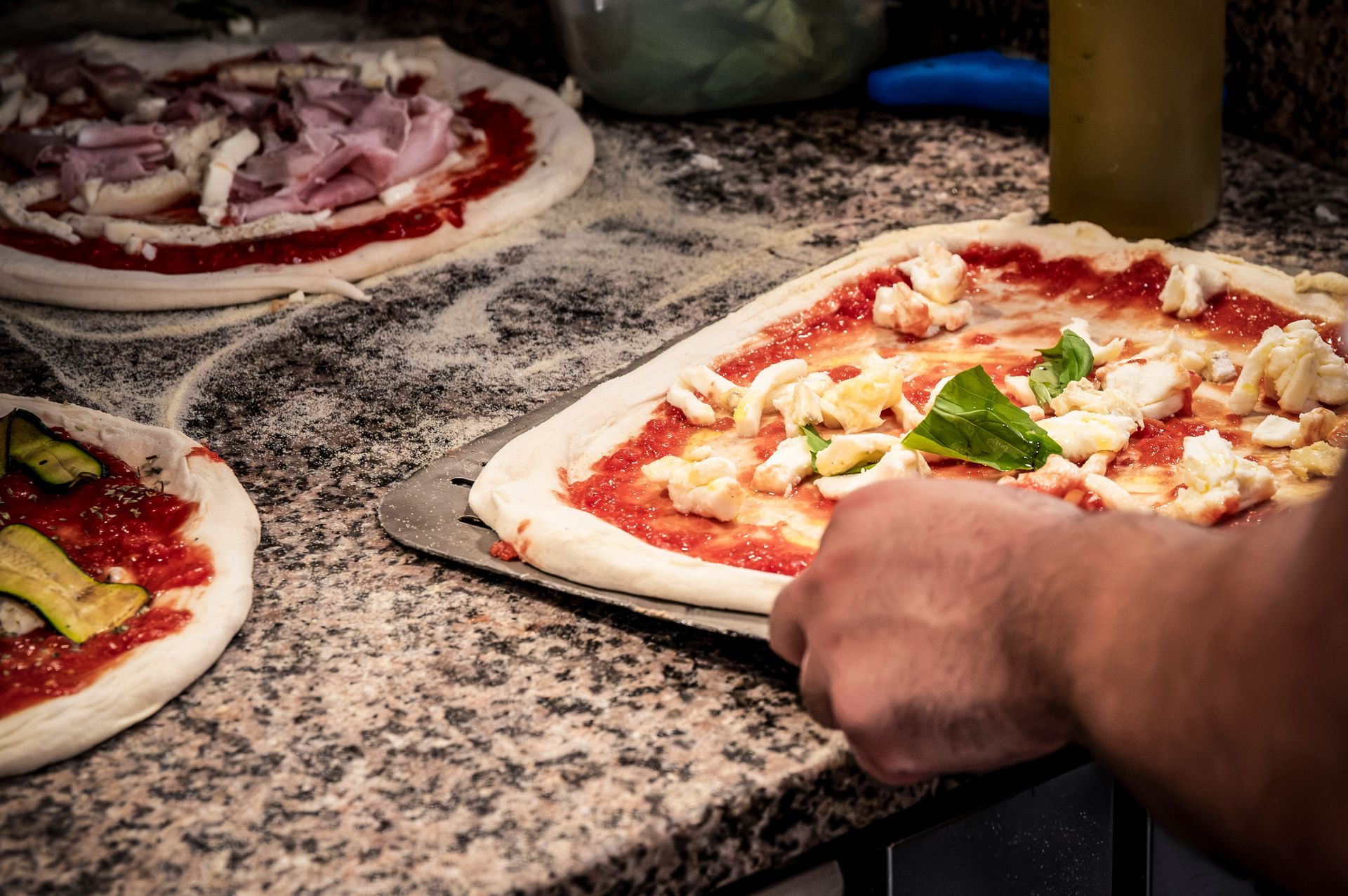 Una persona sta preparando una pizza con salsa di pomodoro e formaggio.