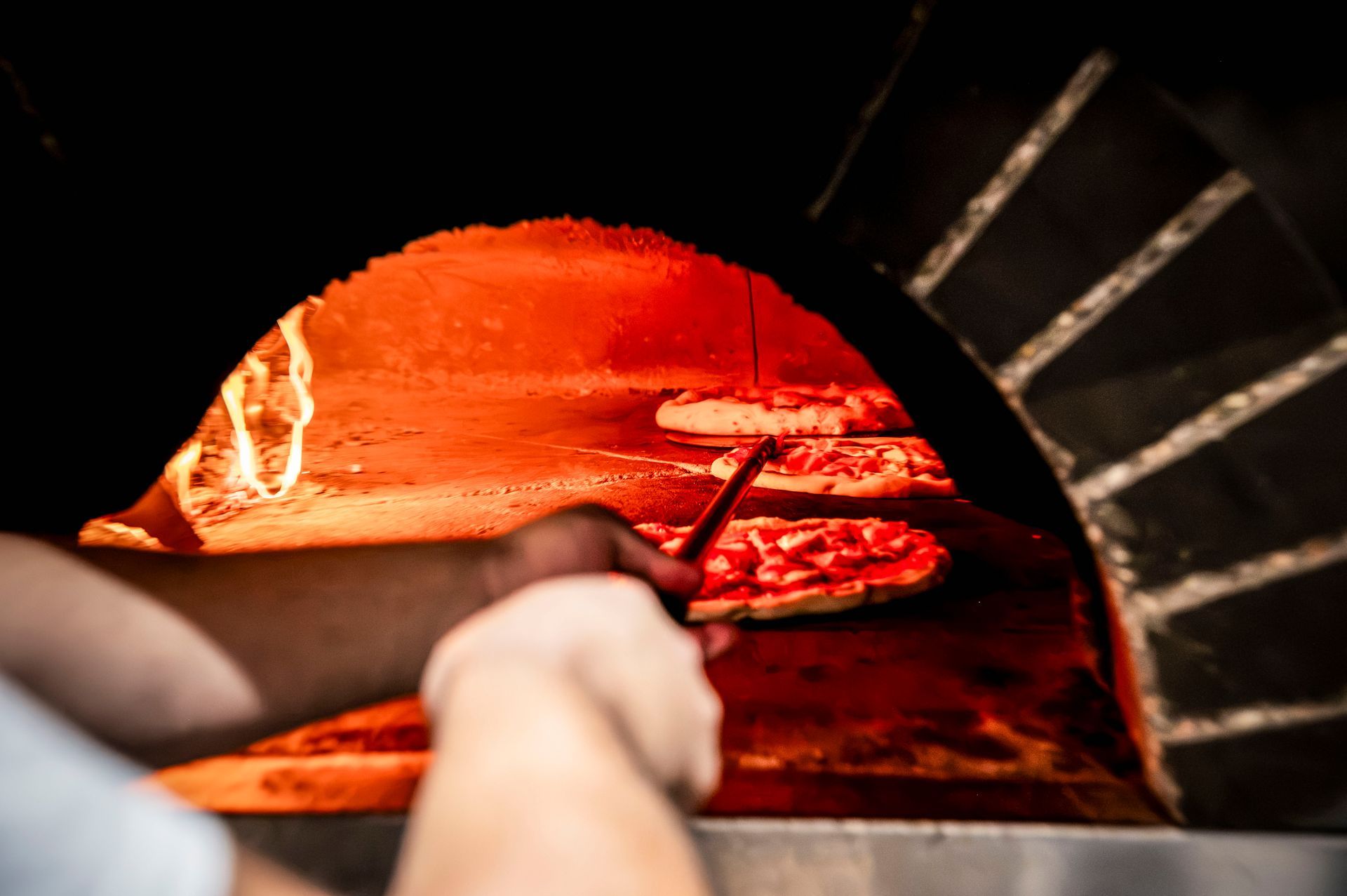 Una persona sta spalmando la salsa di pomodoro sull'impasto della pizza.