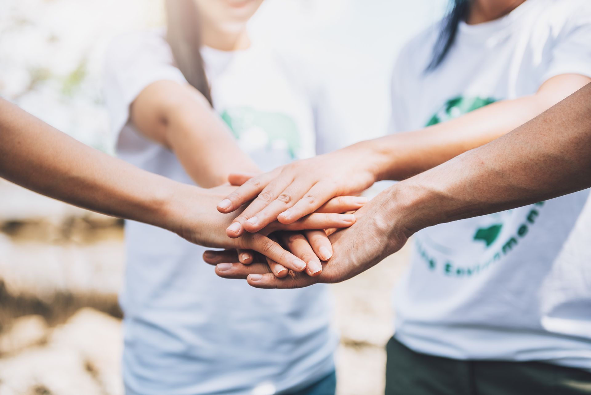 People stacking hands together, signifying teamwork and unity.