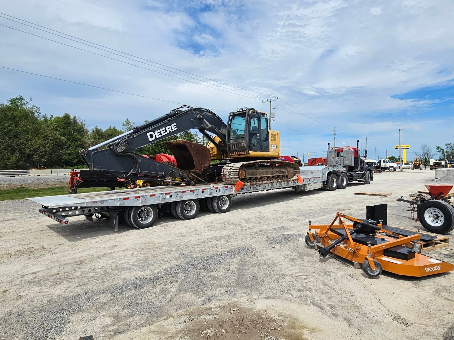 A John Deere excavator loaded on a flatbed trailer, ready for transport.