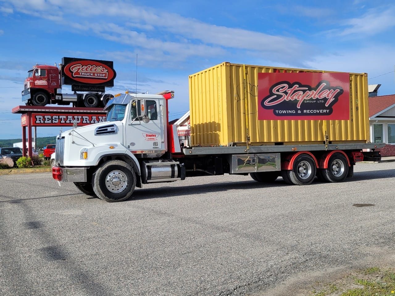 Truck with yellow container and company logo parked outside a restaurant.