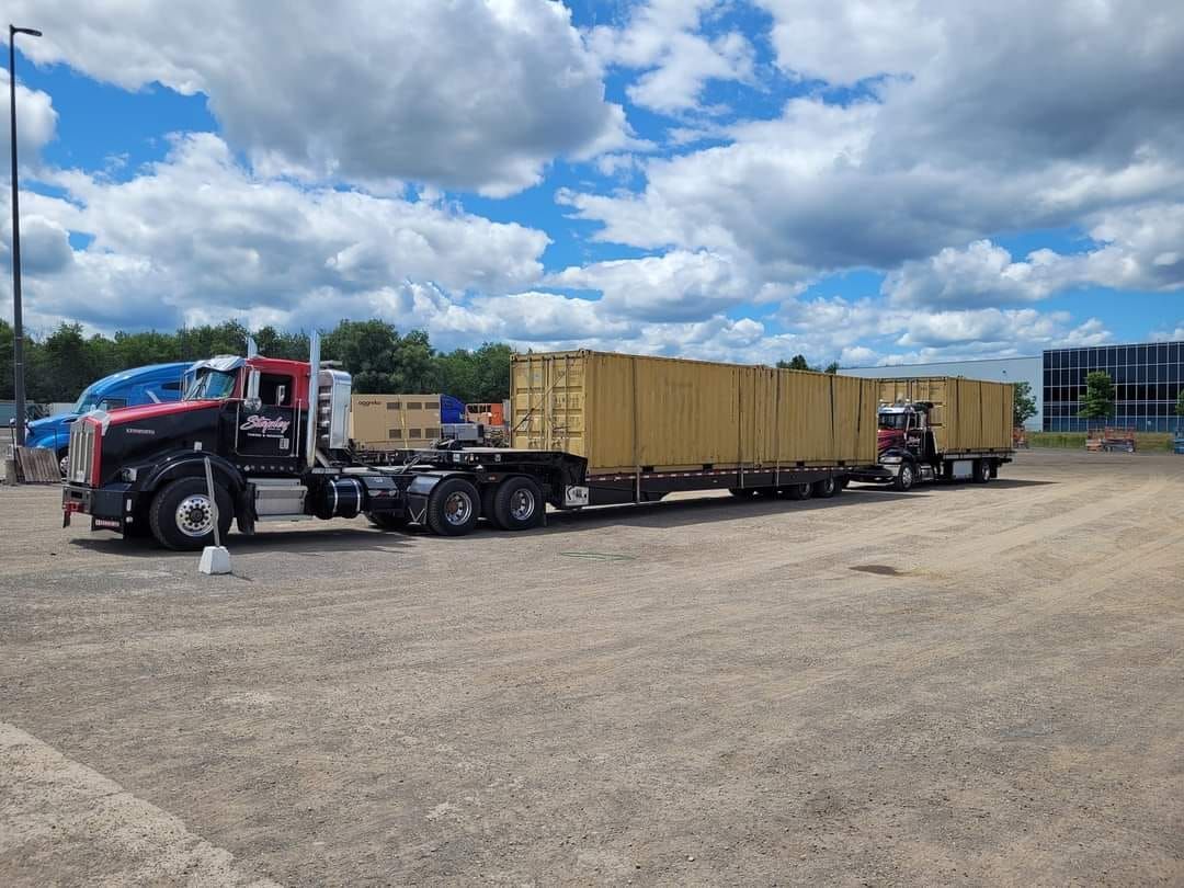 A red and black semi-truck hauling multiple yellow shipping containers on a sunny day.