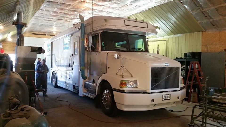 White truck inside a garage. People stand near it. Tools and machinery are visible.
