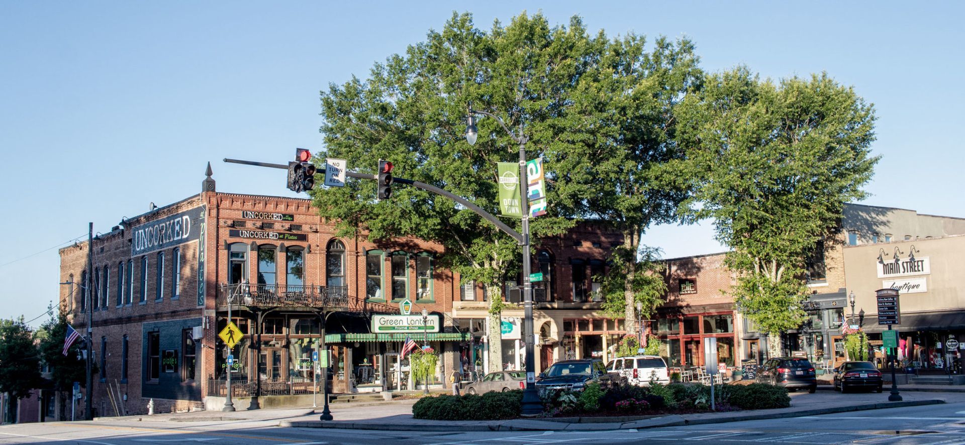 There is a tree in the middle of the street in front of a building.