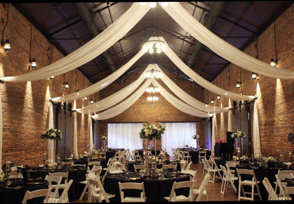 A large room with tables and chairs set up for a wedding reception