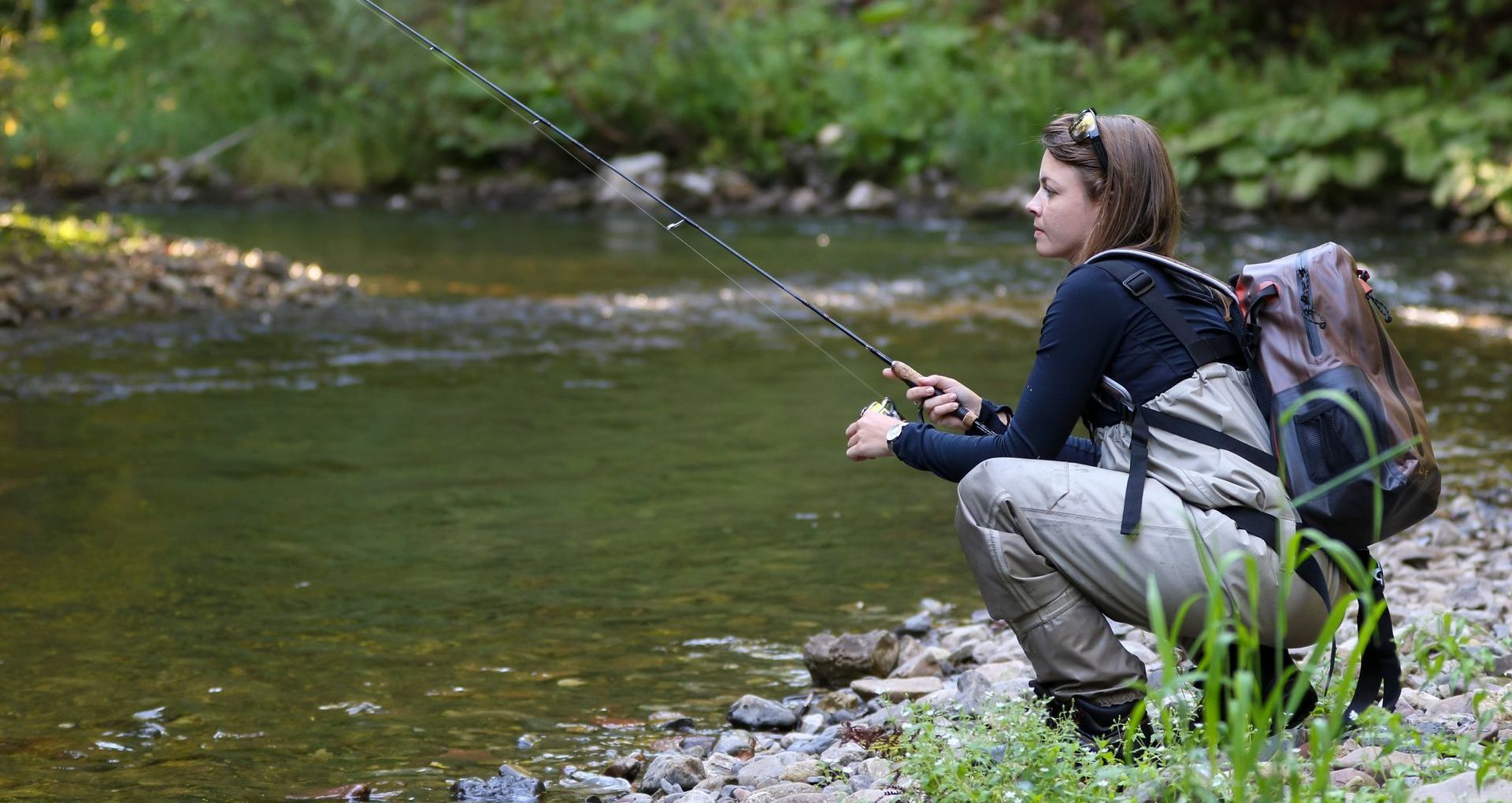 Woman fishing on river bank