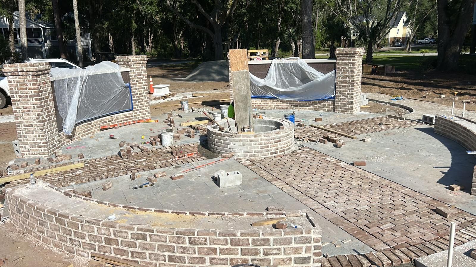 Construction of a brick and stone garden feature with a circular design, outdoors.