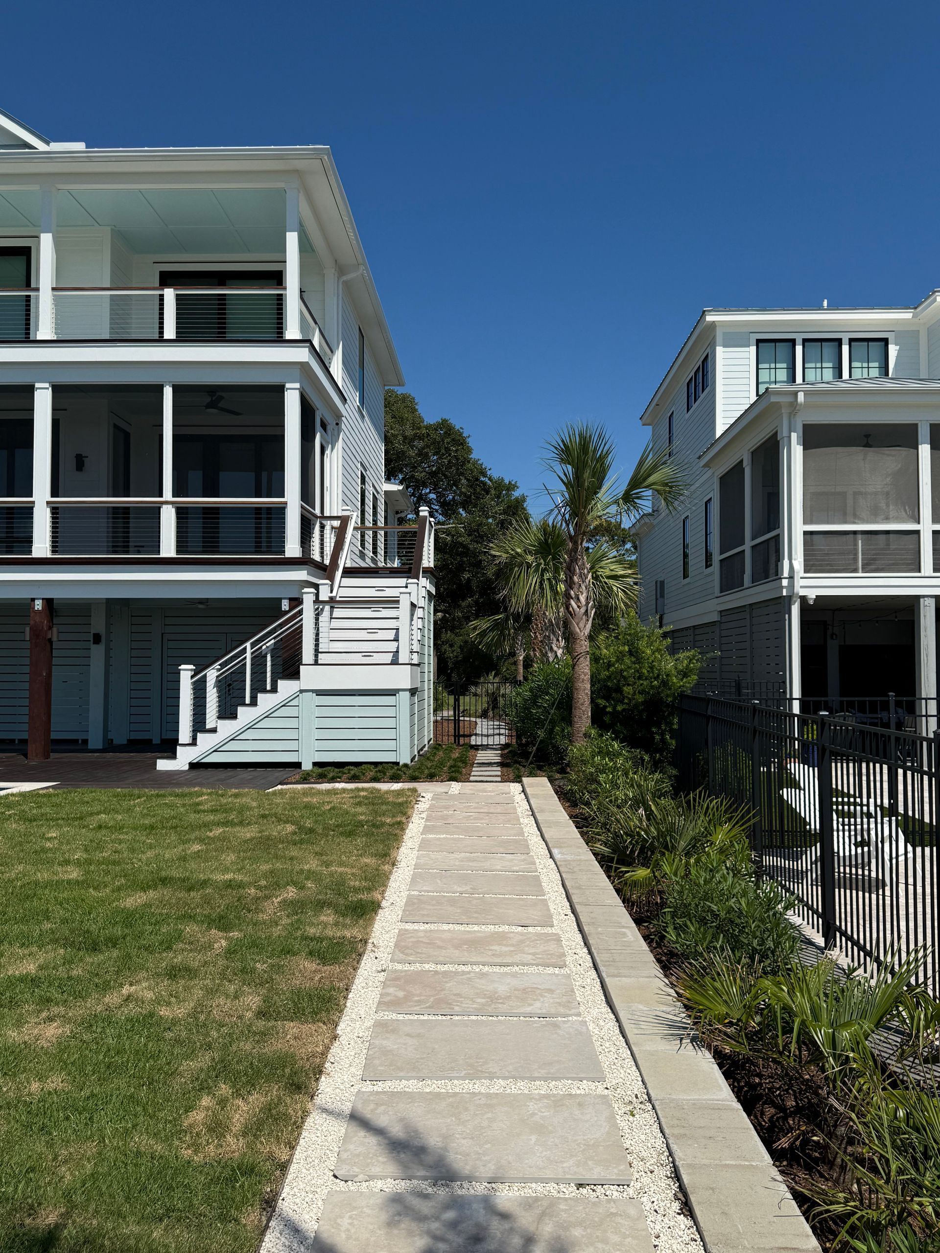 Path between two white houses, bright blue sky.