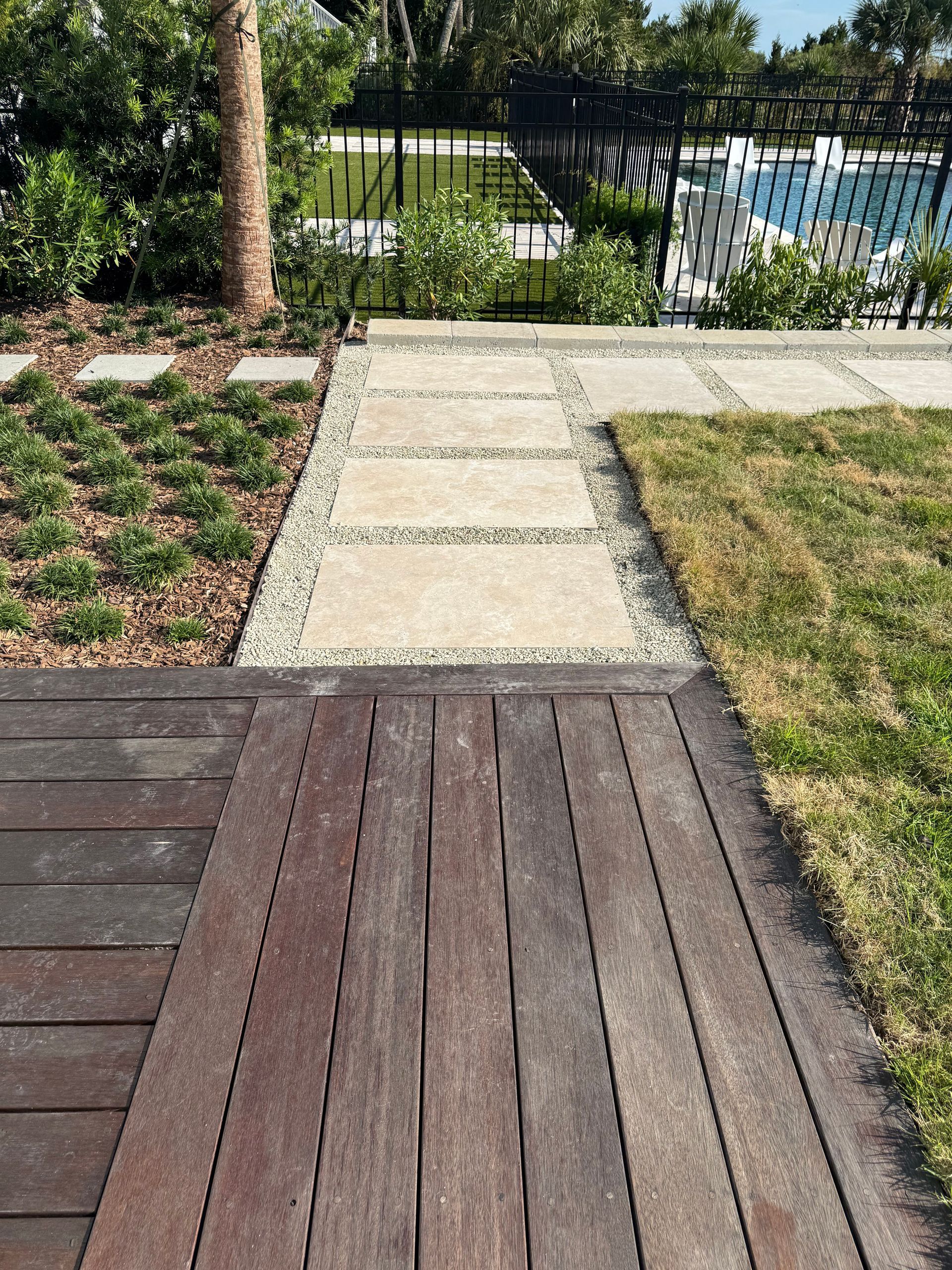 Wooden deck leads to stone path, surrounded by grass and landscaping.