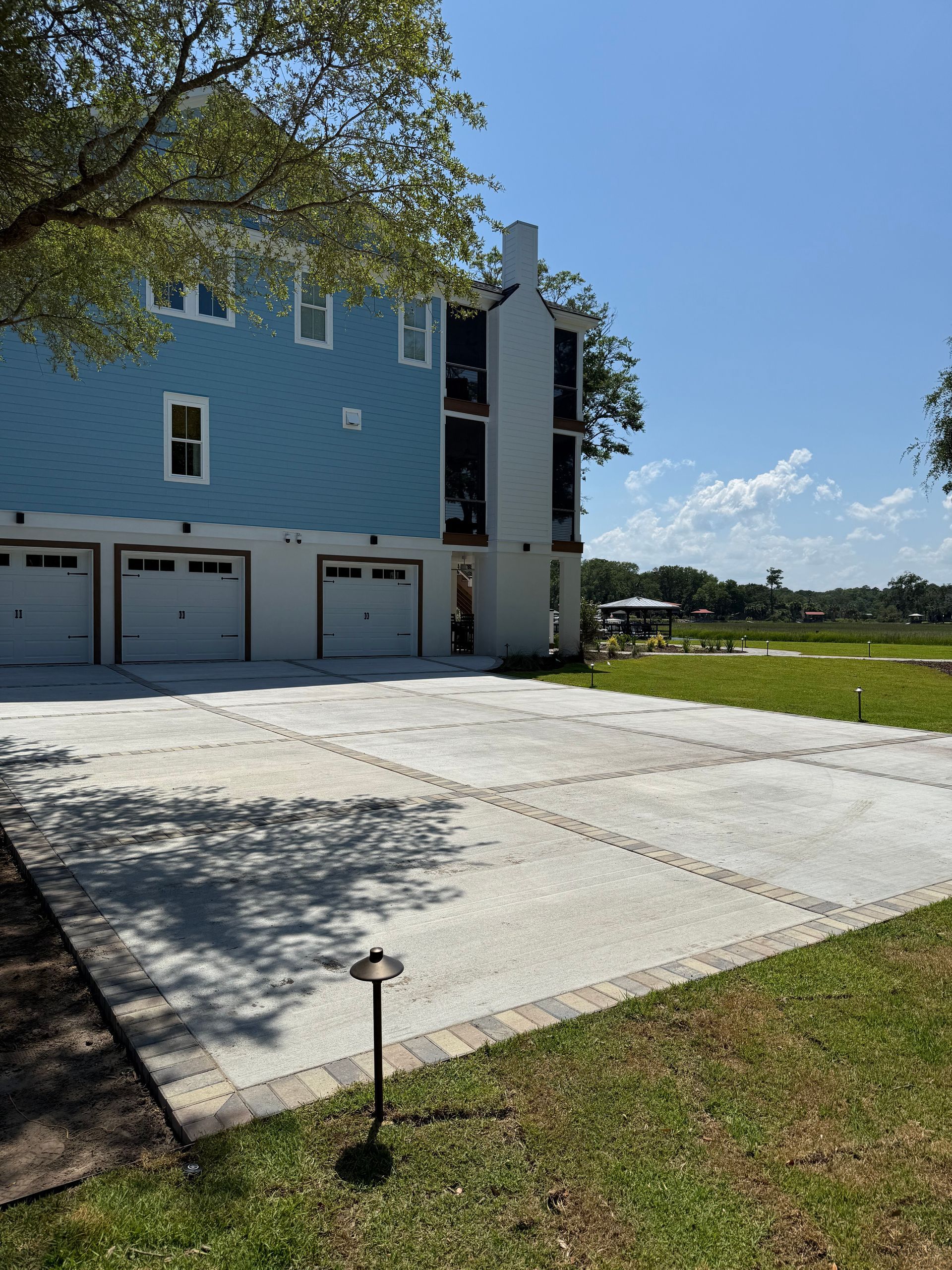 Blue house with white garage doors and concrete driveway on a sunny day.