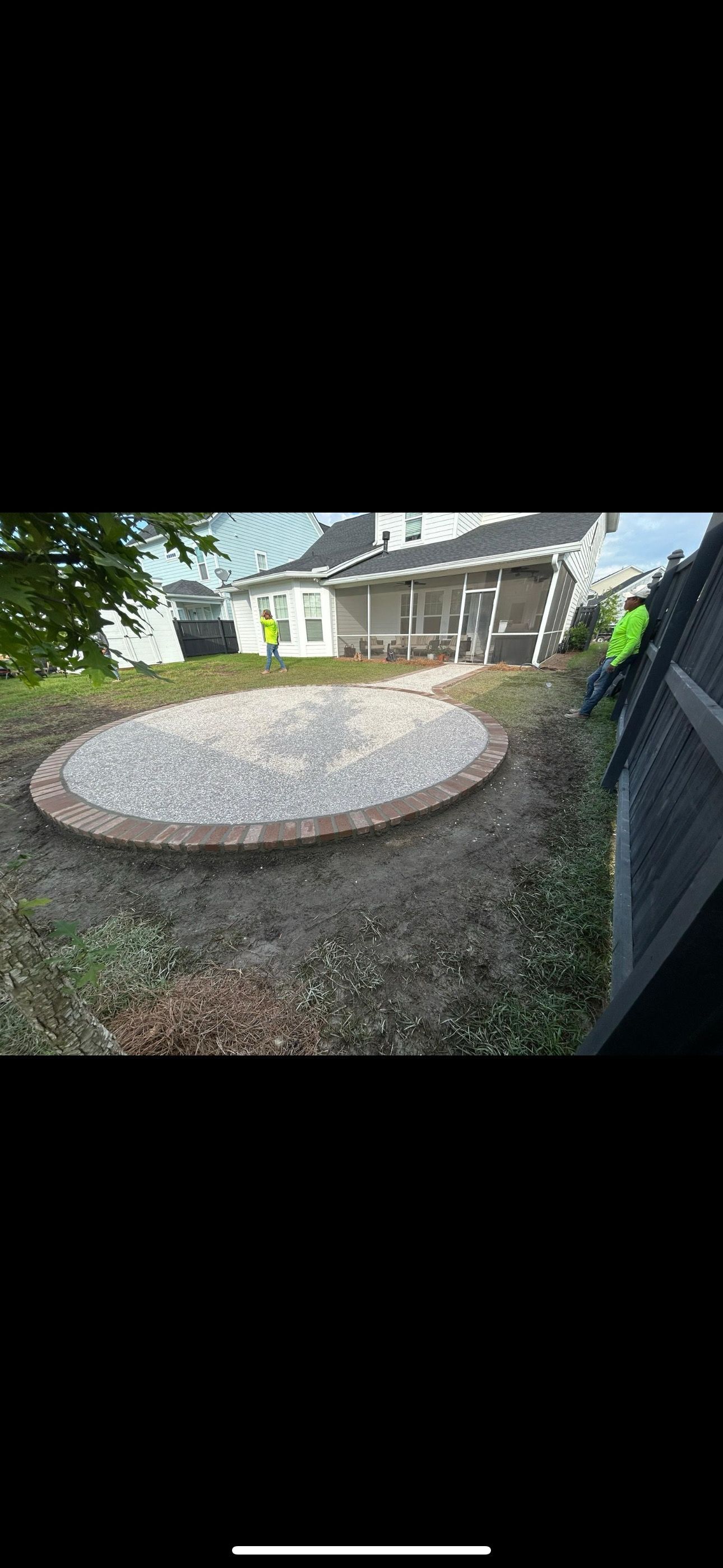 Circular gravel patio in a backyard setting, next to a house.