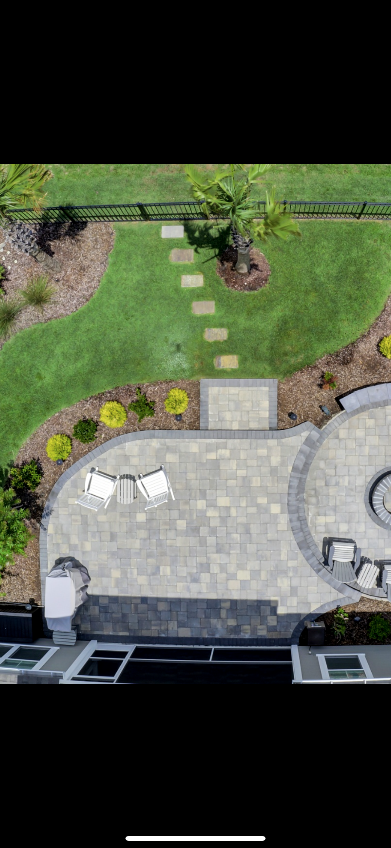 Aerial view of a patio with seating, stone pathway, and green lawn.