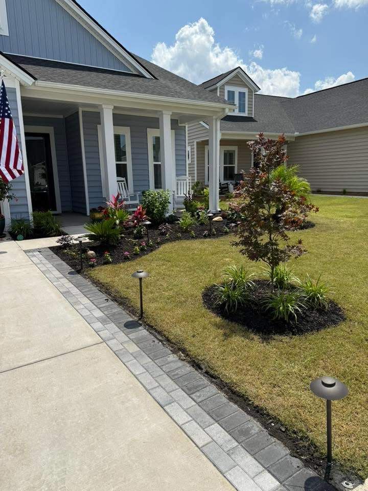 Blue house with porch, landscaped front yard with pavers, and pathway lighting.