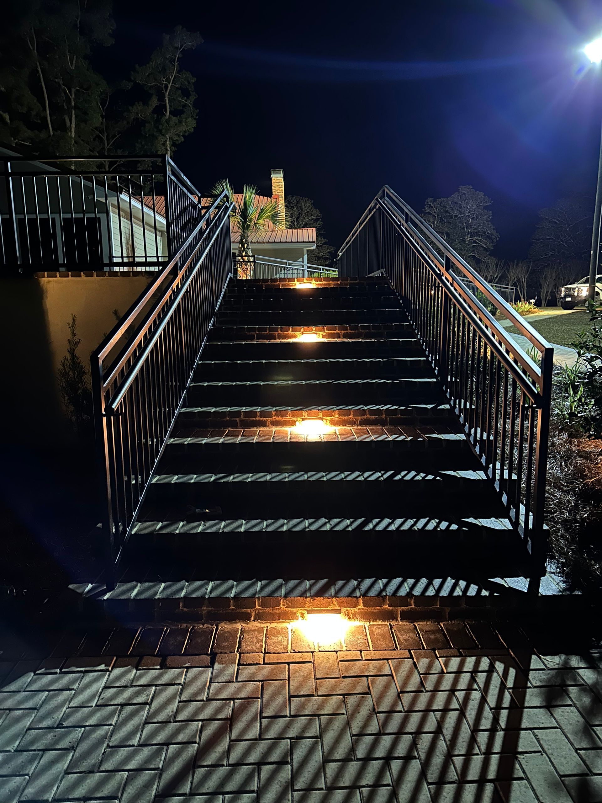 Night shot of outdoor staircase with lit steps, leading to a building.