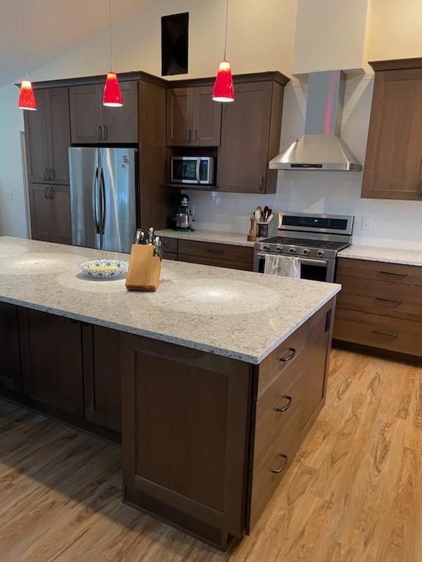 Modern kitchen with island, stainless steel appliances, wood cabinets, and red pendant lights