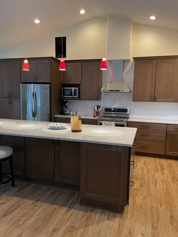 Modern kitchen with dark wood cabinets, stainless appliances, island, and red pendant lights