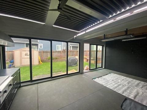 Modern conservatory with black-framed glass walls, gray floor, striped ceiling, and backyard view