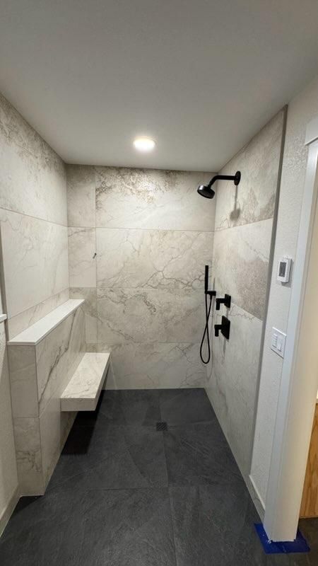 Walk-in shower with large-format tile and a floating bench in a bathroom remodel in Bellingham, WA.