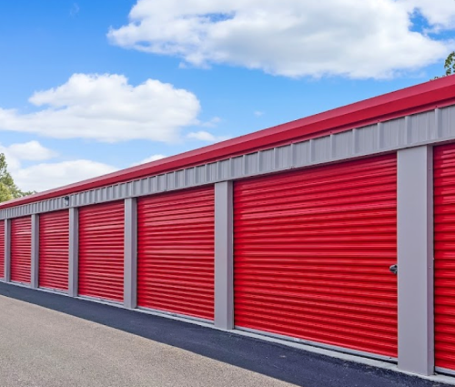 Row of red storage unit doors with gray trim under a blue sky