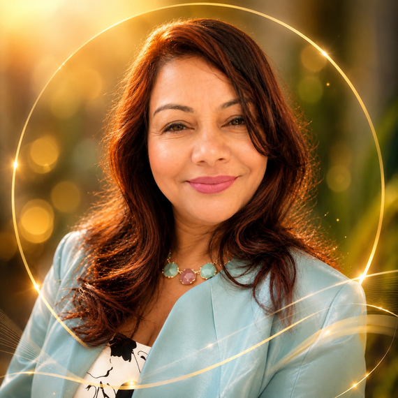 Smiling woman in a light blue jacket against a warm golden bokeh background with glowing rings