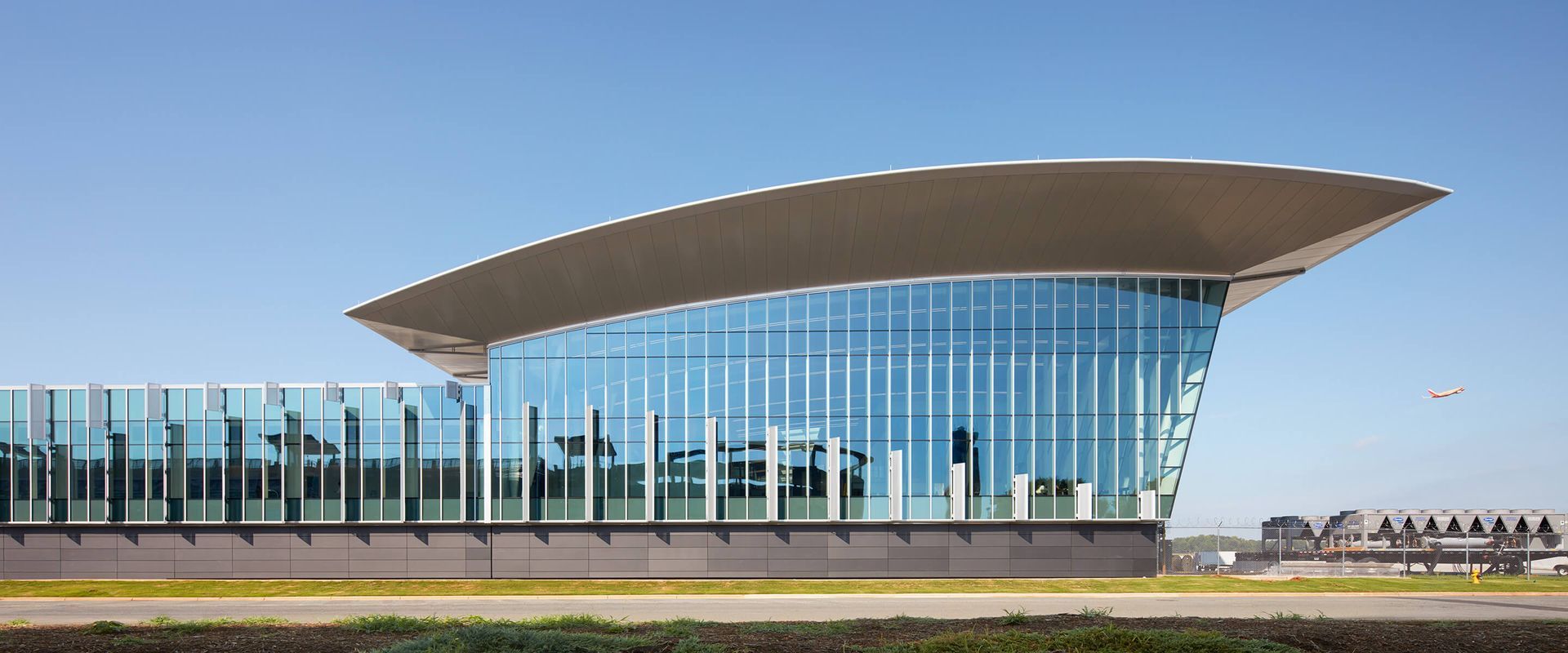 Modern building with curved roof and glass facade against a clear blue sky.