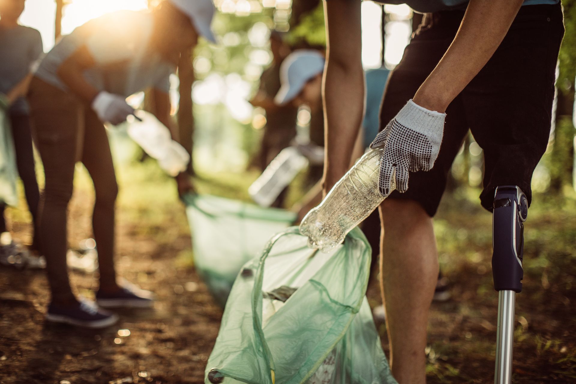 A group of people are picking up trash in the woods.