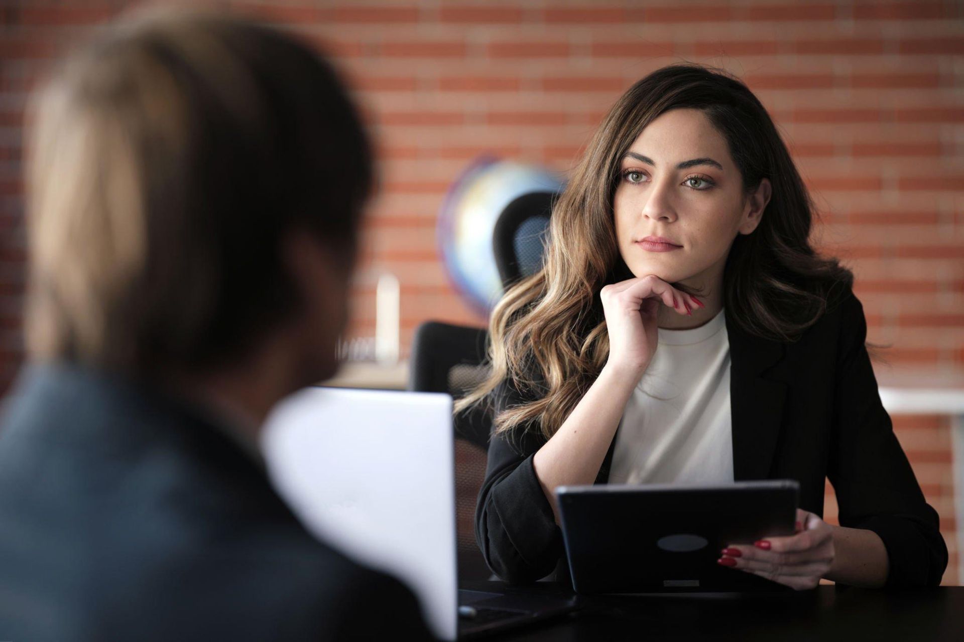 A woman is sitting at a table with a laptop and looking at a man.