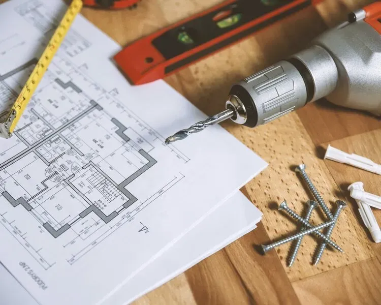 A drill is sitting on top of a house plan