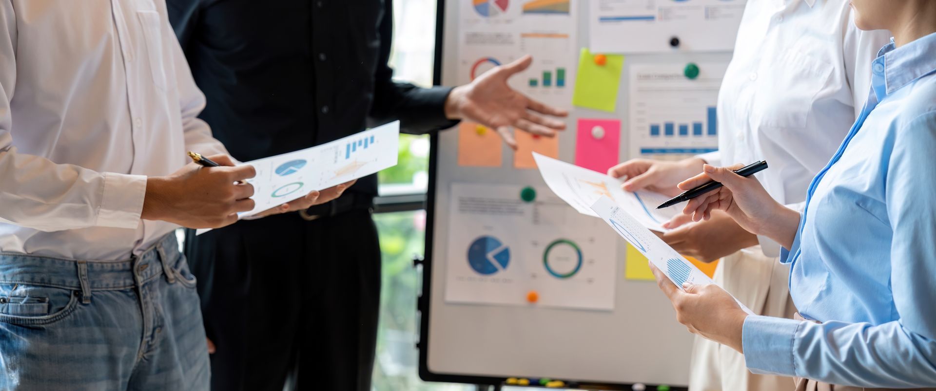 A group of people are having a meeting in front of a whiteboard.