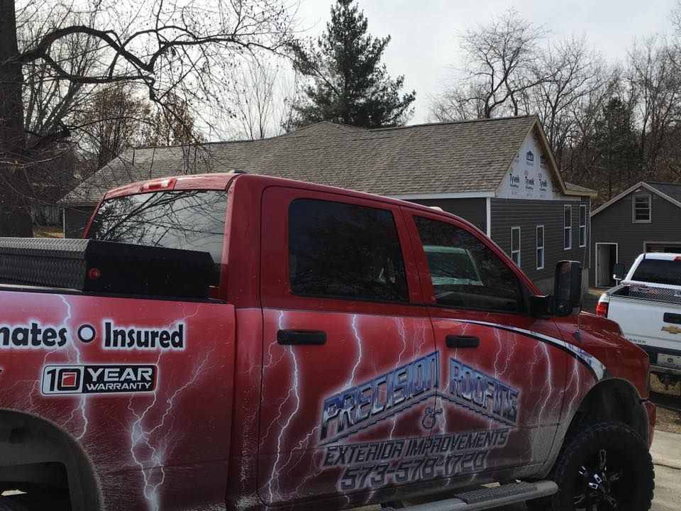 Red pickup truck with custom graphics parked in a suburban driveway under bare trees