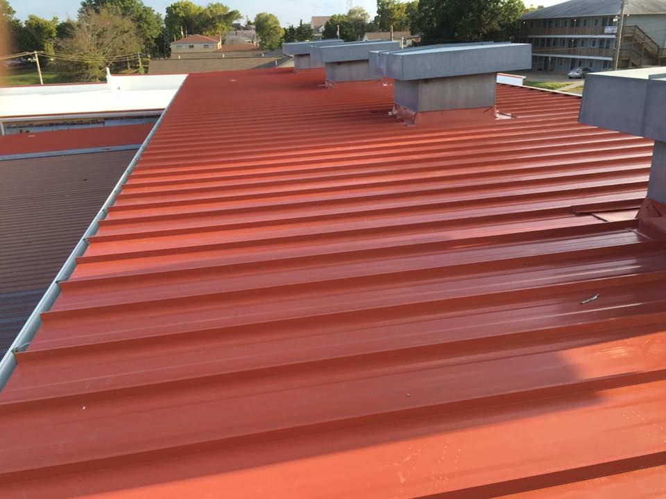 Red corrugated metal roof with skylights and vents on a building