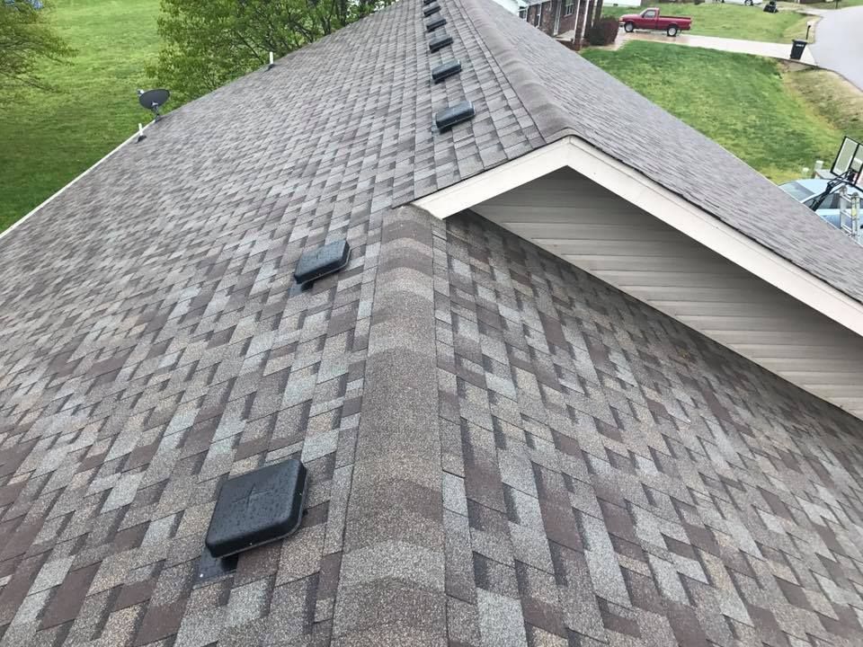 Roof with gray shingles and several black vents beside a white-sided dormer.