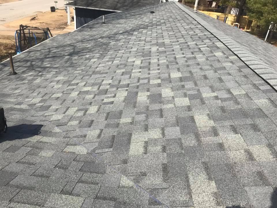 Gray shingled roof viewed from above, with trees and ground visible at the edges.