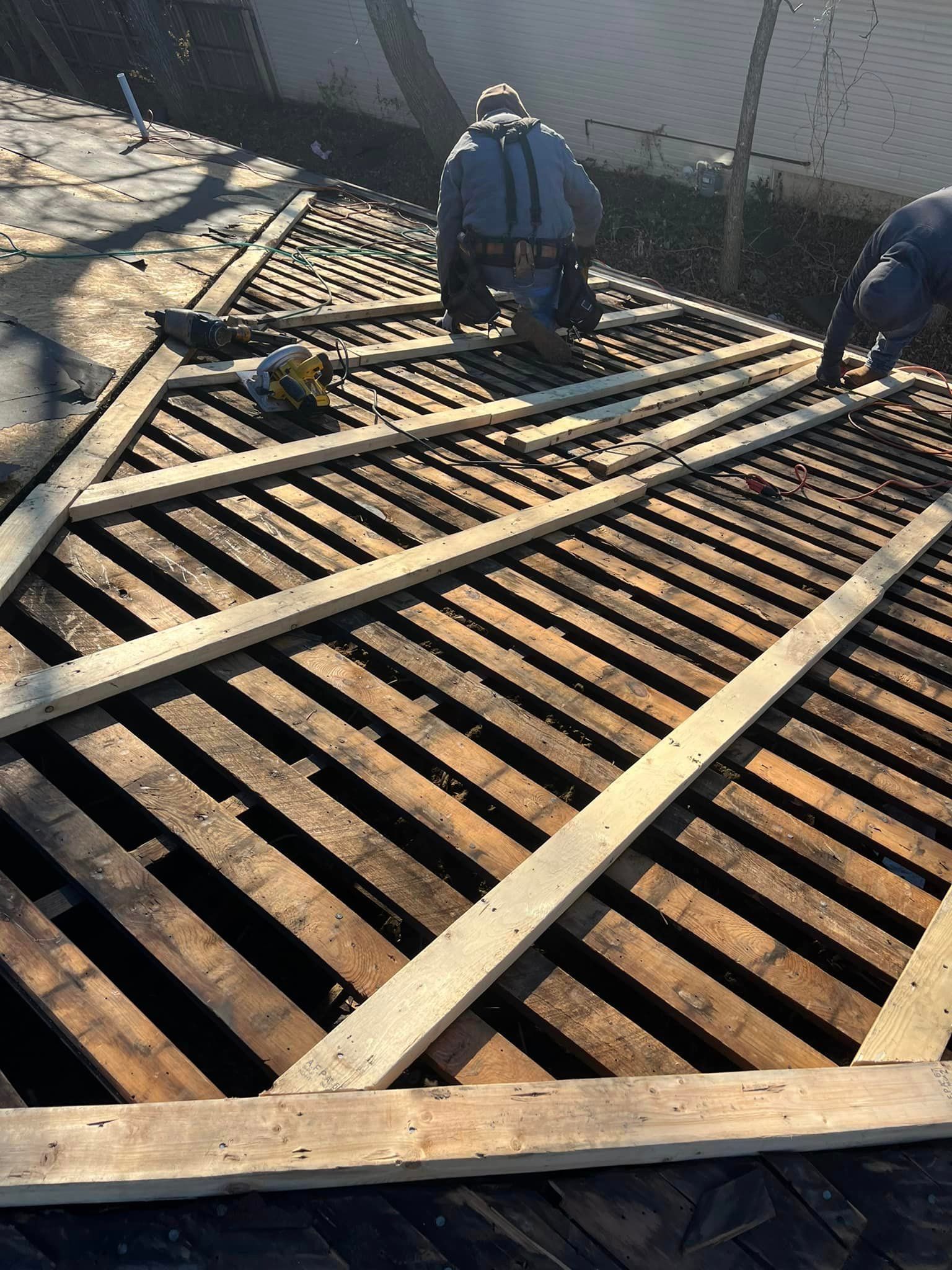 Workers installing wooden decking over a sloped metal grate outdoors