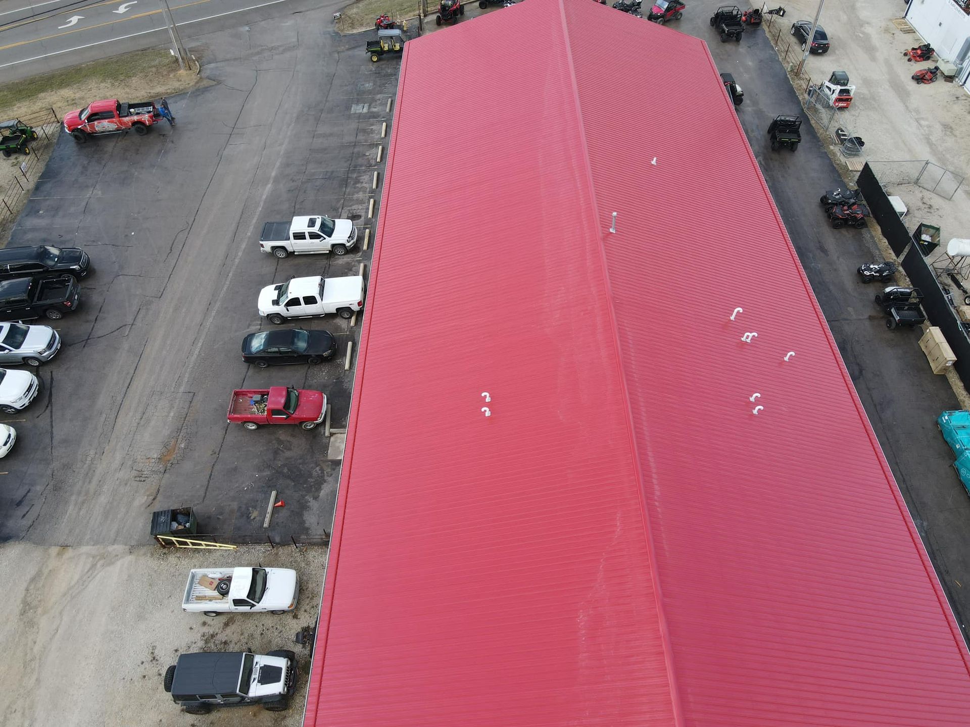 Aerial view of a large red-roofed building with parked cars along both sides