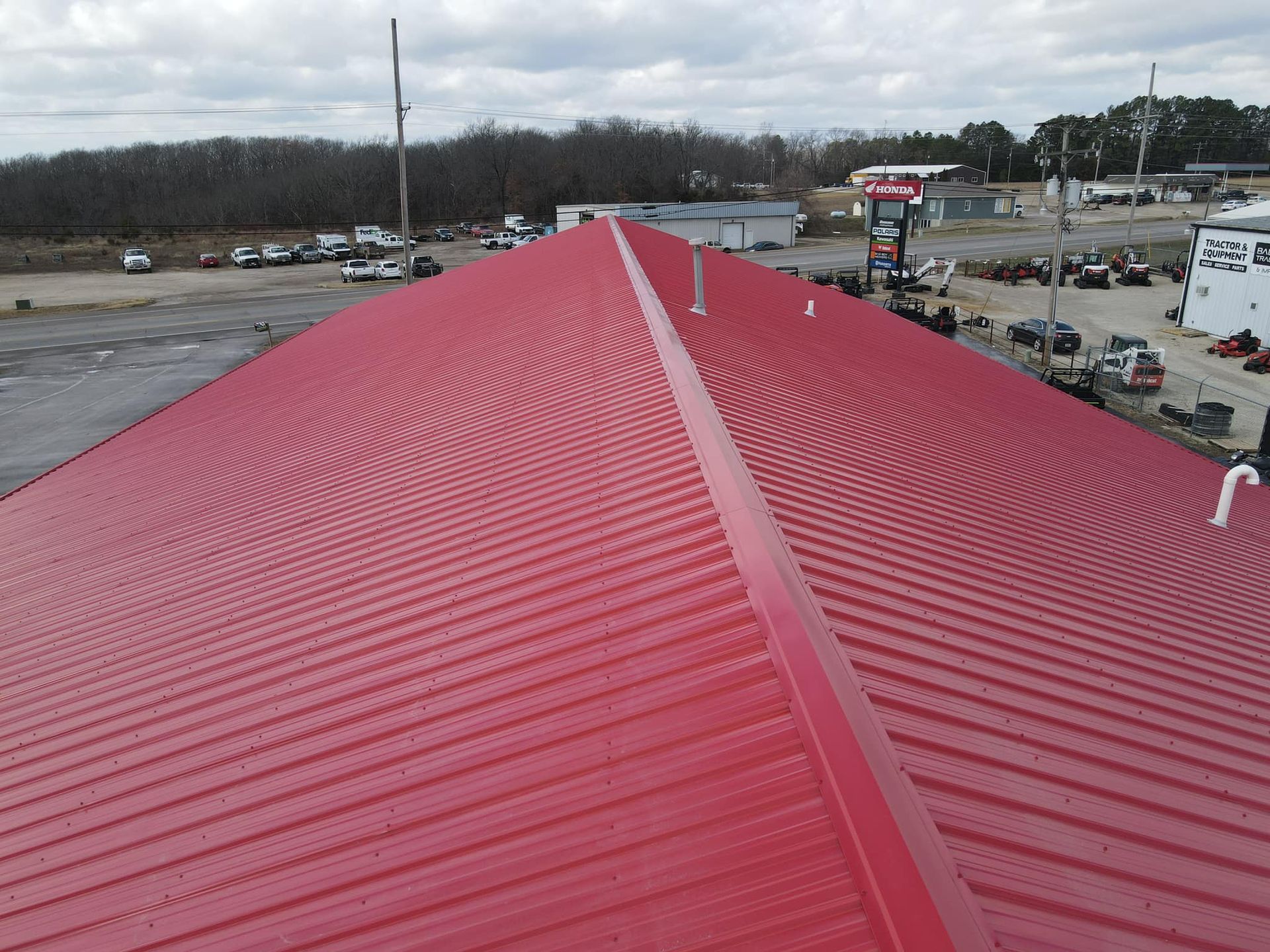 Red metal roof with a central ridge, viewed from above in an industrial area