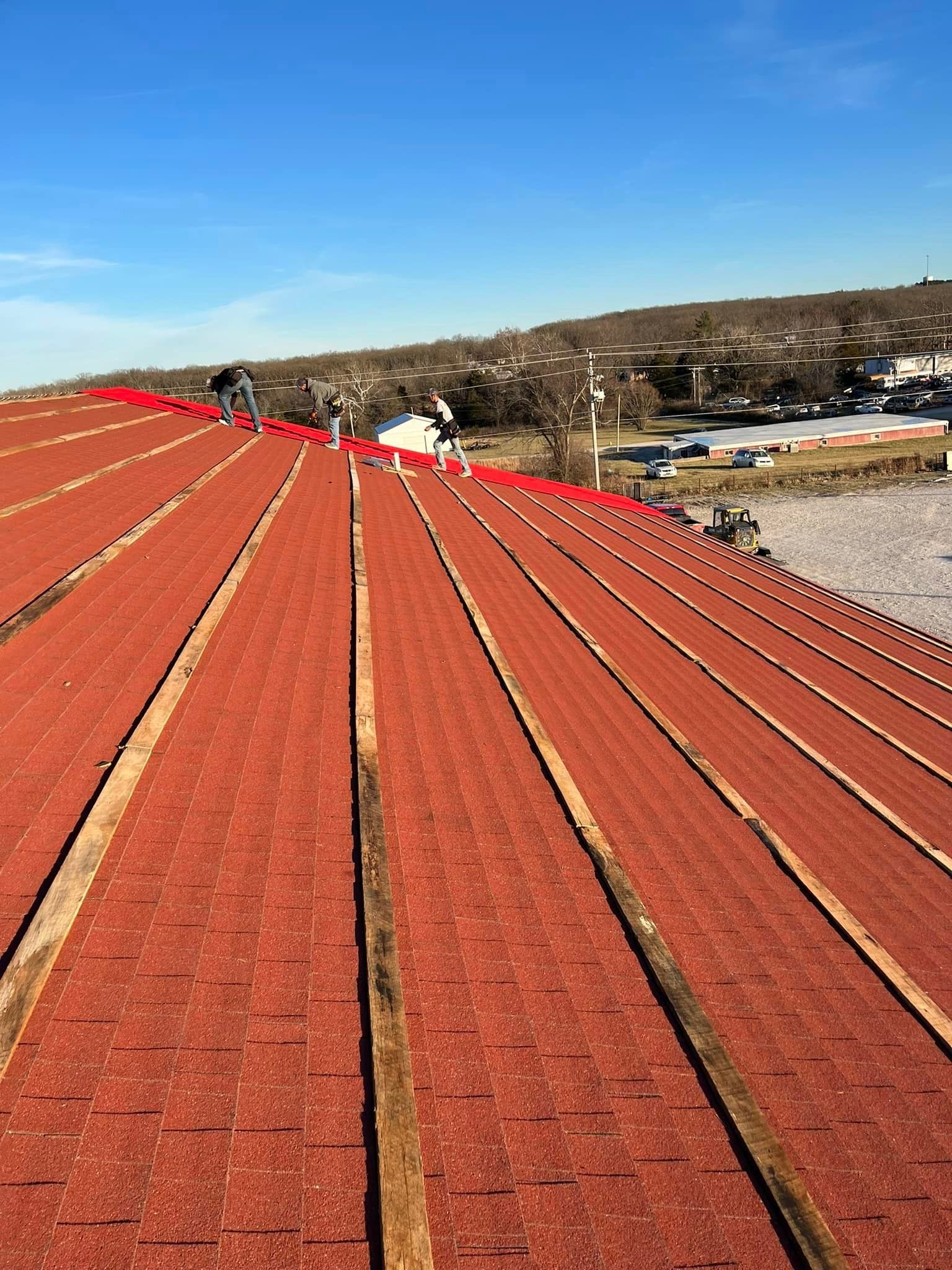Red corrugated metal roof stretching toward a hillside under a clear blue sky