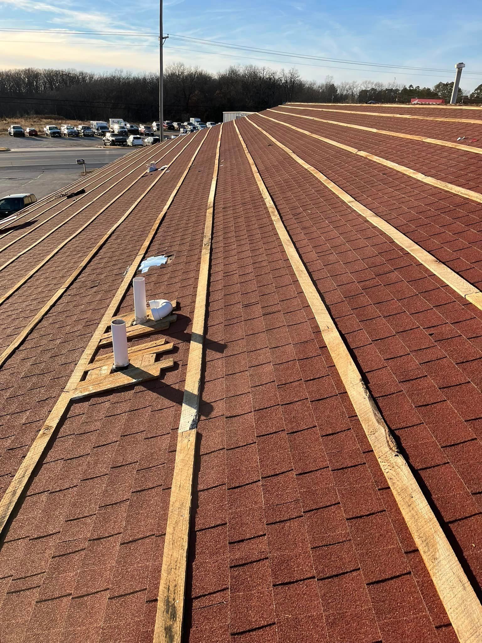 Solar rooftop with rows of red shingles and yellow rails under a clear sky.