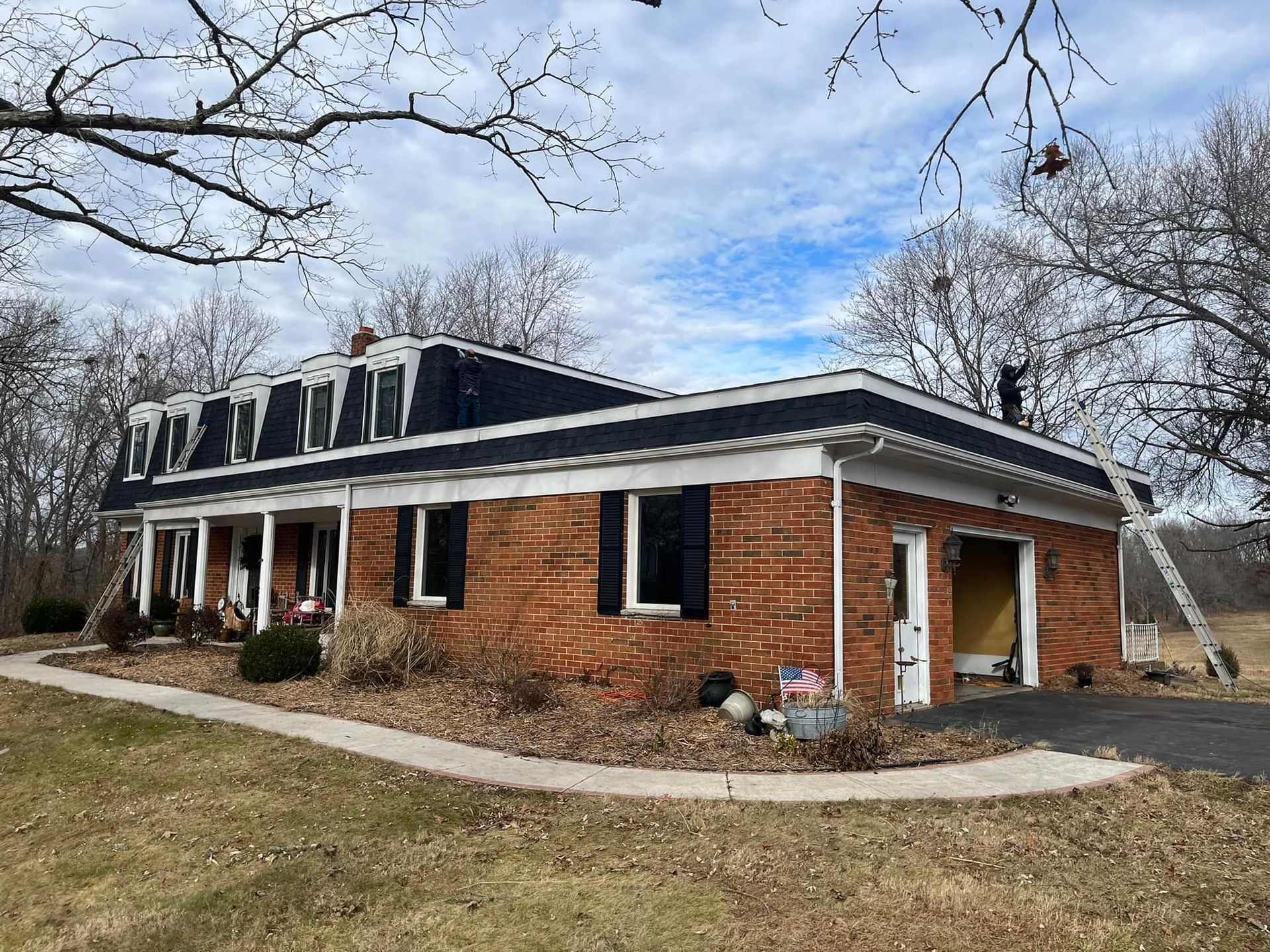 Single-story brick house with a dark roof and white trim in a winter yard