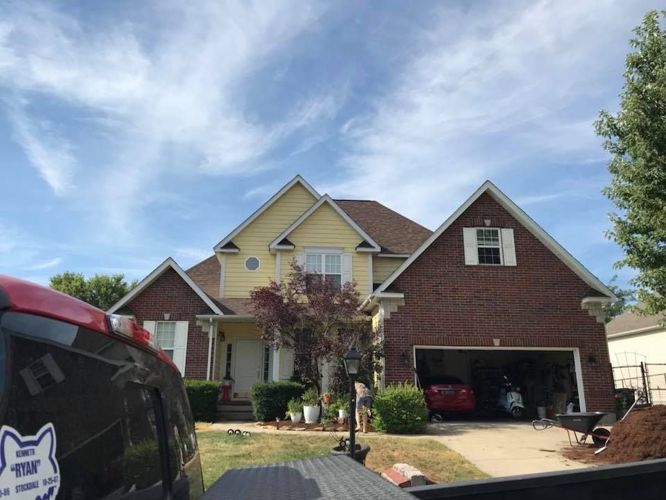 Suburban two-story brick and siding house with attached garage under a bright blue sky