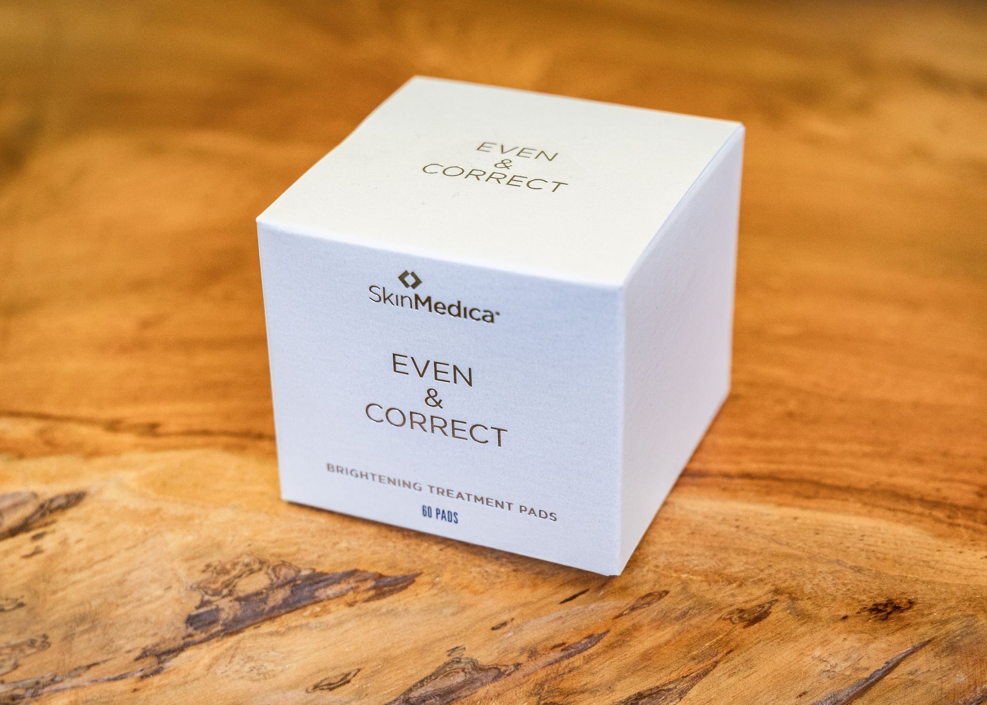 White skincare box labeled “Even & Correct” on a wooden surface