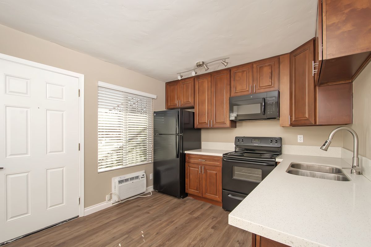 a kitchen with wooden cabinets and a black refrigerator