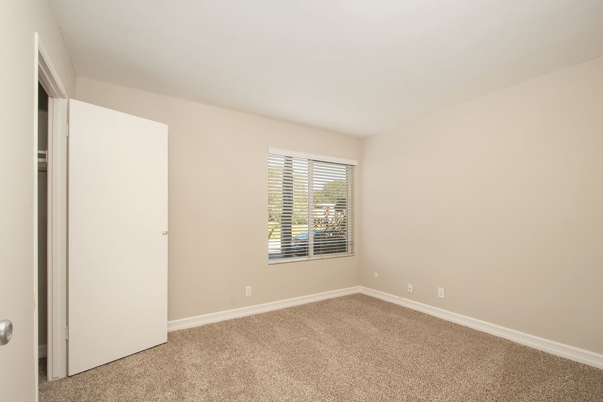 an empty bedroom with a window and a closet .
