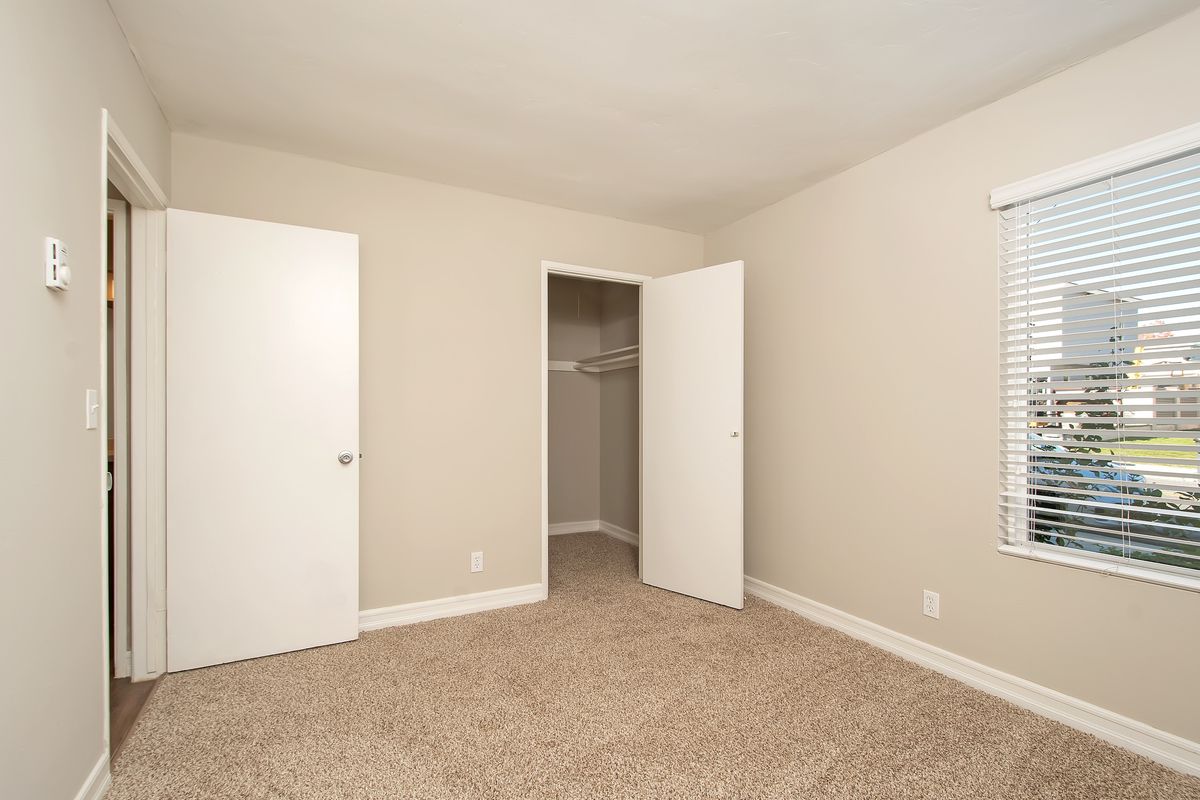 an empty bedroom with a closet and a window .
